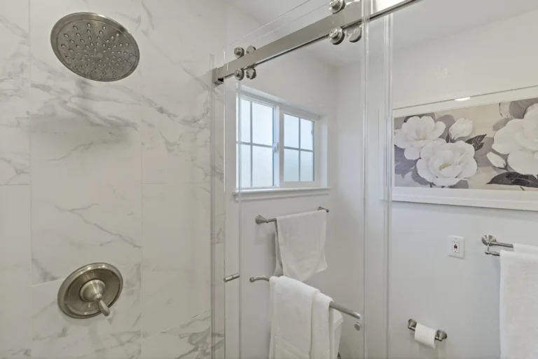 Mission Viejo shower close‑up with hex mosaic floor and marble‑look walls.