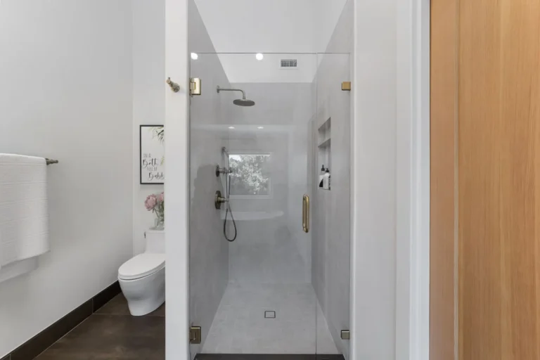 Walk-in shower with a rainfall head and tiled niche in a Santa Ana master bathroom remodel