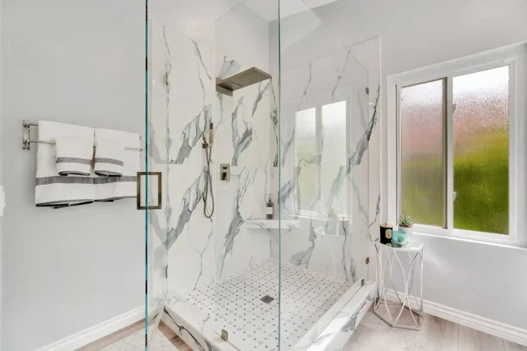 Frameless glass walk-in shower with mosaic tile floor in a remodeled Laguna Hills primary bathroom.