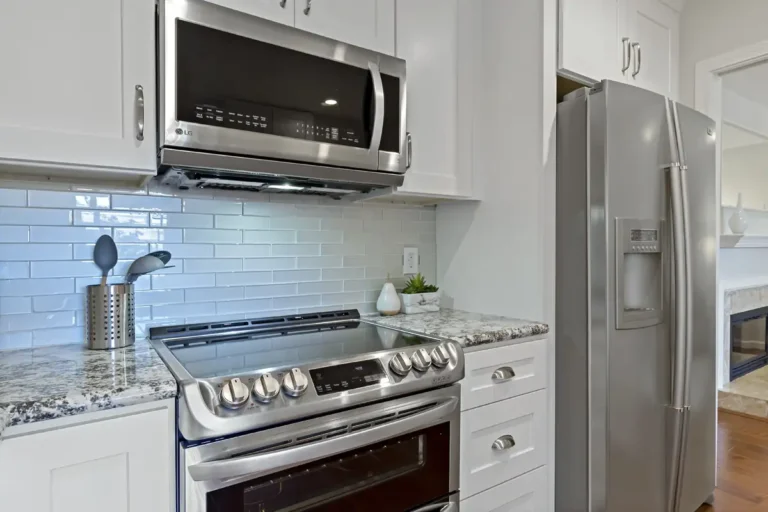 Over the range microwave and side by side refrigerator against pale glass tile in a Laguna Hills kitchen remodel