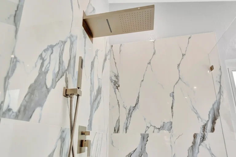 Brushed nickel rainfall shower head on marble-look porcelain tile in a Laguna Hills bathroom.