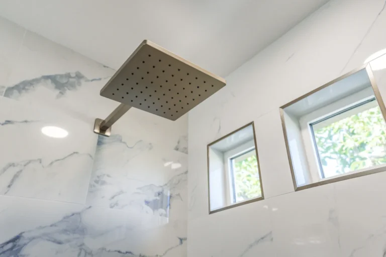 Square rain shower head below two tiled windows in a remodeled bathroom in Irvine, California