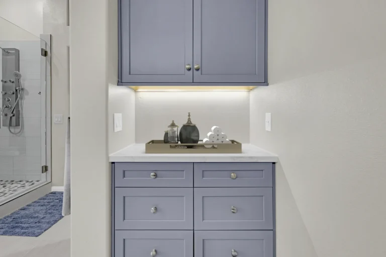 Blue linen tower with under-cabinet lighting and a quartz counter in a Carlsbad primary bathroom remodel