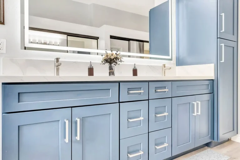 Brushed nickel fixtures and a backlit mirror above the blue shaker vanity in a Laguna Hills bathroom.