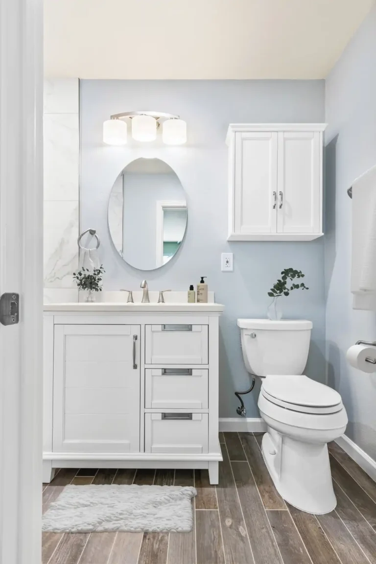 White shaker vanity with an oval mirror, wall cabinet and toilet in a remodeled Mission Viejo bathroom
