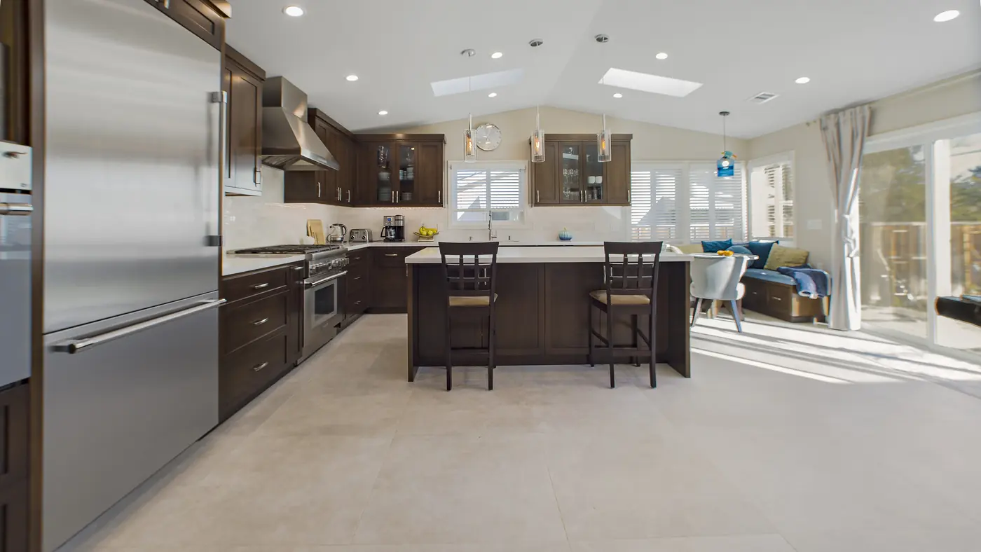 Espresso shaker island with two counter stools and a built-in stainless refrigerator in an Irvine kitchen remodel
