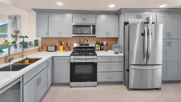 Gray shaker cabinets with crown molding and white countertops frame a stainless gas range in a Carlsbad kitchen remodel