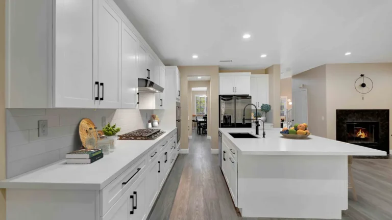 White shaker cabinets with black pulls and a long island with a black sink in an open layout Corona kitchen remodel
