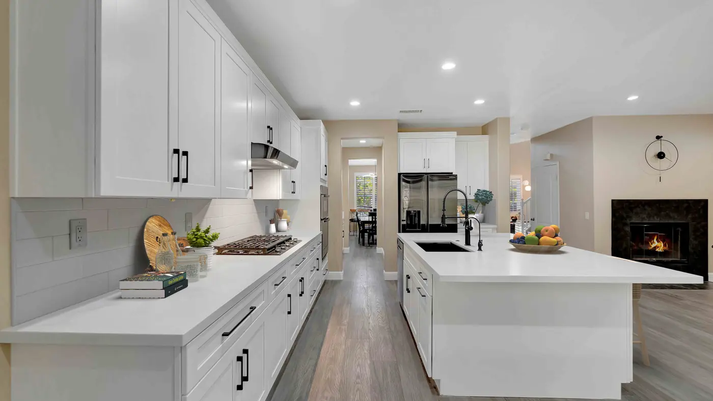 White shaker cabinets with black pulls and a long island with a black sink in an open layout Corona kitchen remodel
