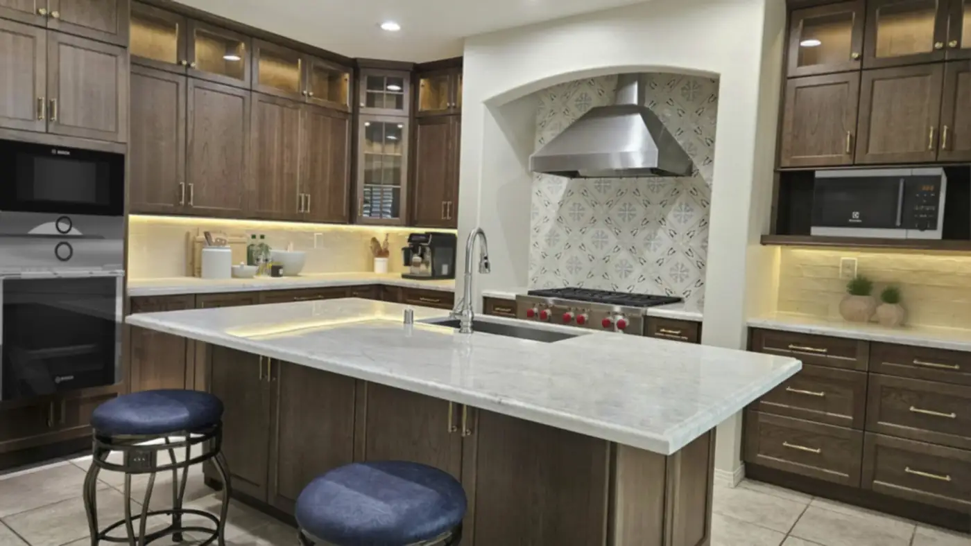 Dark wood cabinets with brass pulls and a white marble island with barstools in a remodeled Costa Mesa kitchen