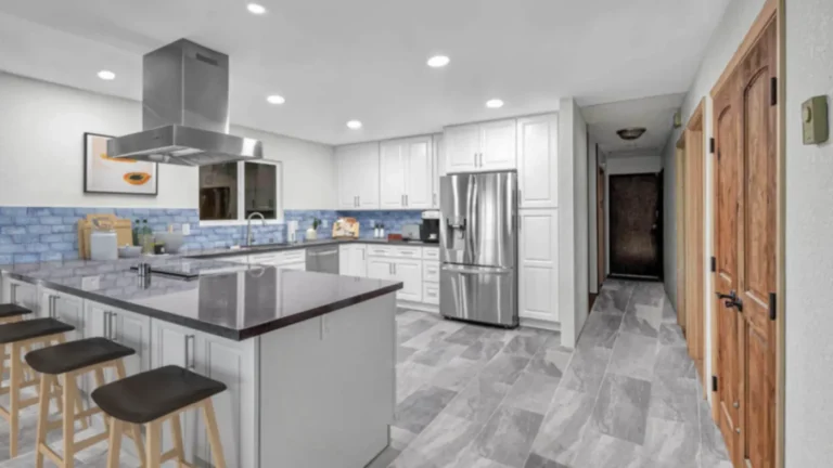 Gray slate-look tile floors and white cabinets in a wide view of a remodeled Laguna Hills kitchen with peninsula seating