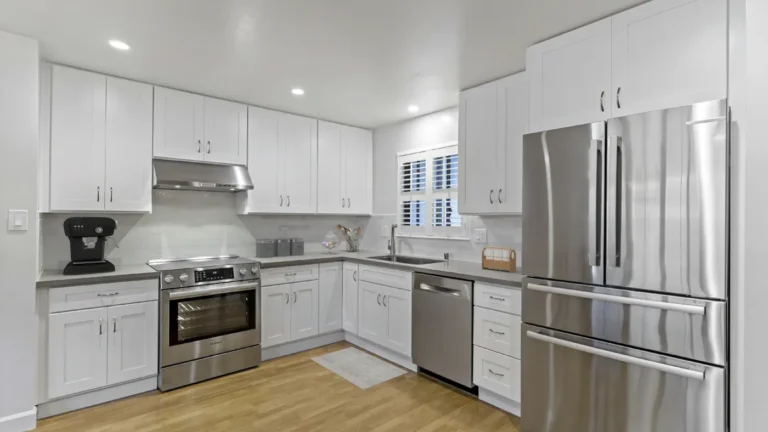White shaker cabinets and stainless steel appliances wrap a bright corner kitchen remodel in Laguna Hills, California