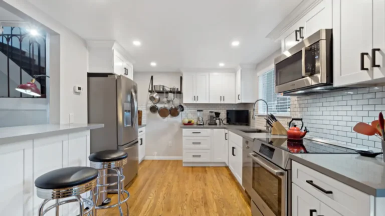 White shaker cabinets and subway tile backsplash in a Laguna Niguel kitchen remodel with a gray peninsula and oak floors