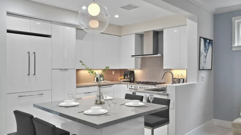 Gray quartz island with seating for four under a glass globe pendant in a white gloss Mission Viejo kitchen remodel
