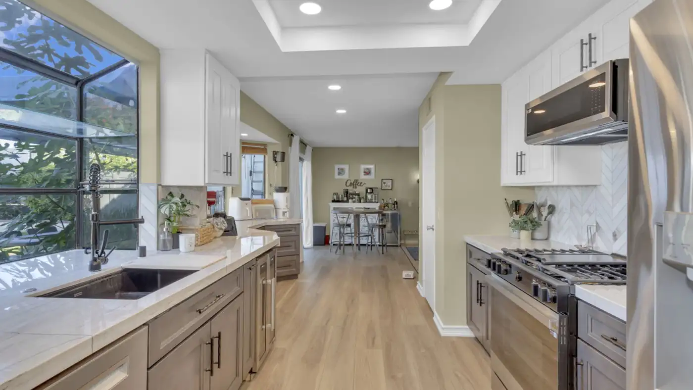 Galley kitchen remodel in Oceanside with two-tone cabinets, quartzite countertops, and a garden window over the sink