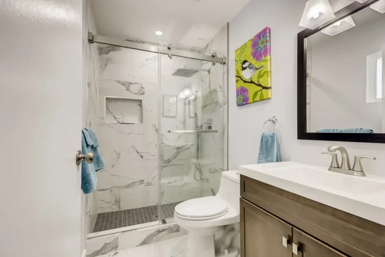 Walk-in shower with marble-look porcelain tile and sliding glass door in a Newport Beach bathroom remodel