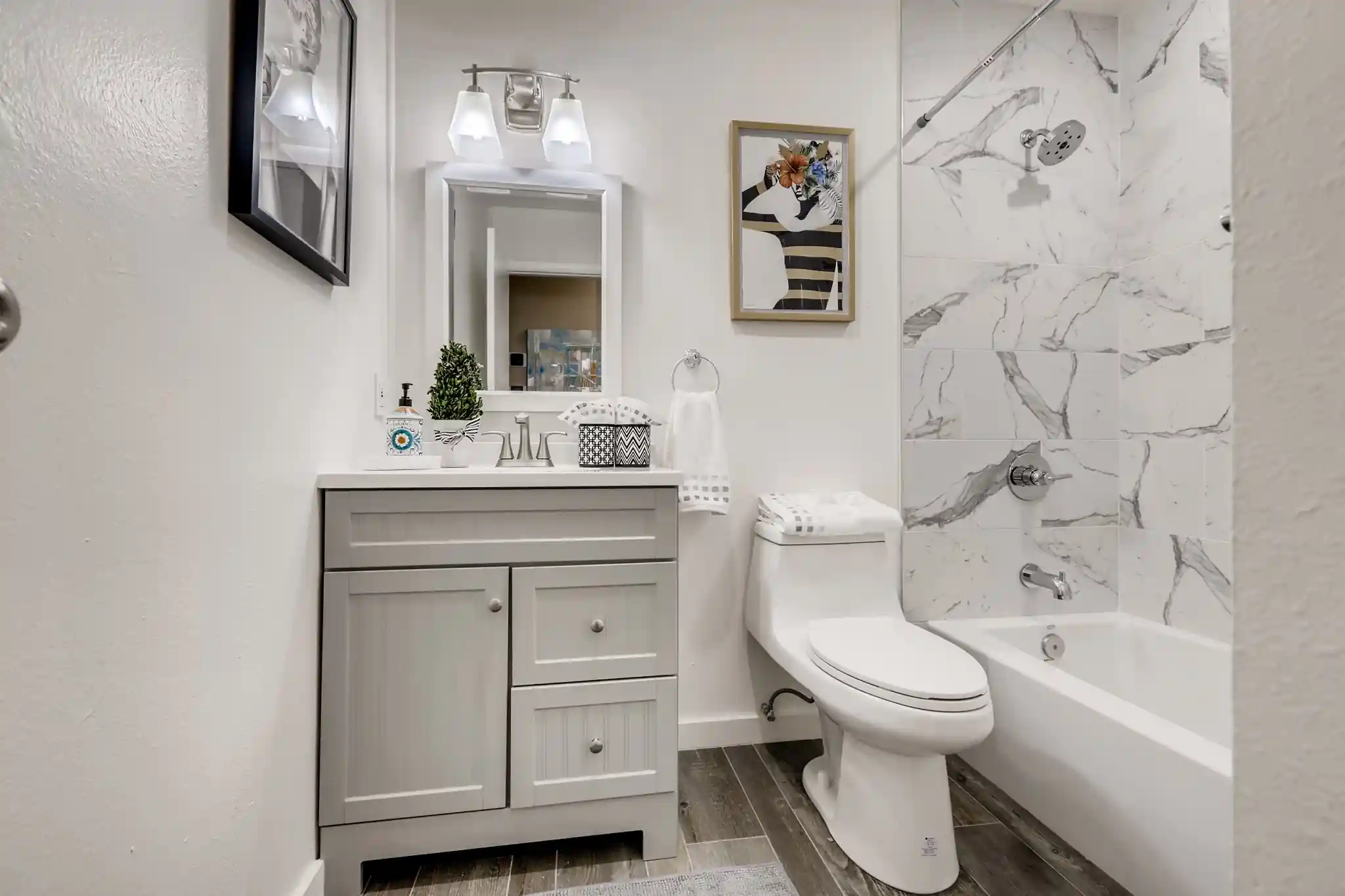 Wide view of a remodeled San Clemente guest bathroom with a gray shaker vanity and marble look tub shower combo