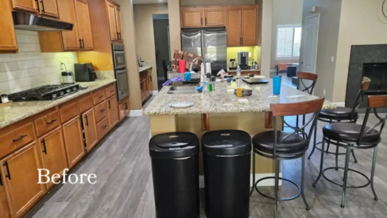 Before photo of the Corona kitchen with honey oak cabinets, granite counters, and a cluttered island with stools