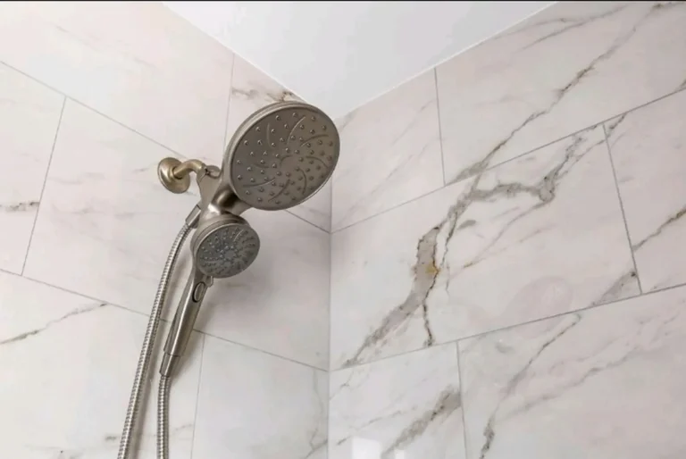 Brushed nickel dual showerhead mounted in the corner of a marble tiled shower in a Laguna Niguel bathroom