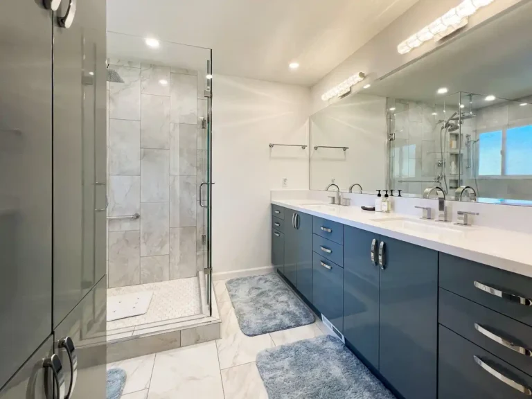 Aliso Viejo master bathroom after remodeling, with a blue double vanity and frameless corner glass shower.