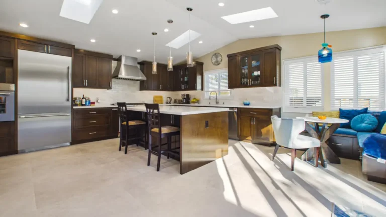 Skylights and a vaulted ceiling brighten dark wood cabinets and island seating in a custom kitchen renovation in Irvine