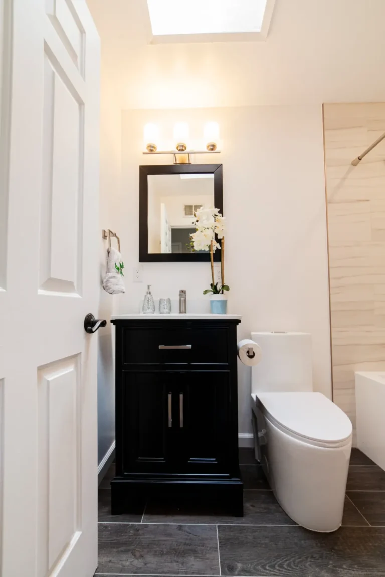 Black single-sink vanity beneath a framed mirror and skylight in a remodeled Irvine bathroom.