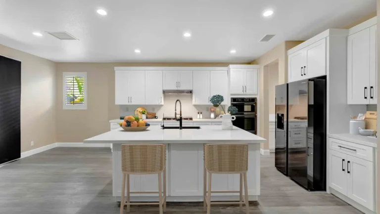 Large white quartz island with two woven counter stools facing white shaker cabinets in a remodeled Corona kitchen