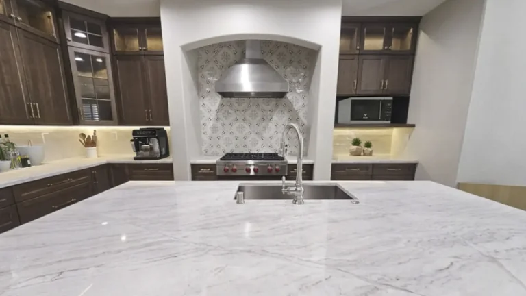 White marble island with an undermount sink facing an arched tile range alcove in a remodeled Costa Mesa kitchen