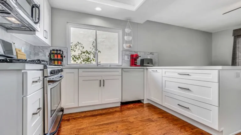 Gray marble-look tile backsplash above white shaker drawers and a stainless dishwasher in this Irvine kitchen remodel.