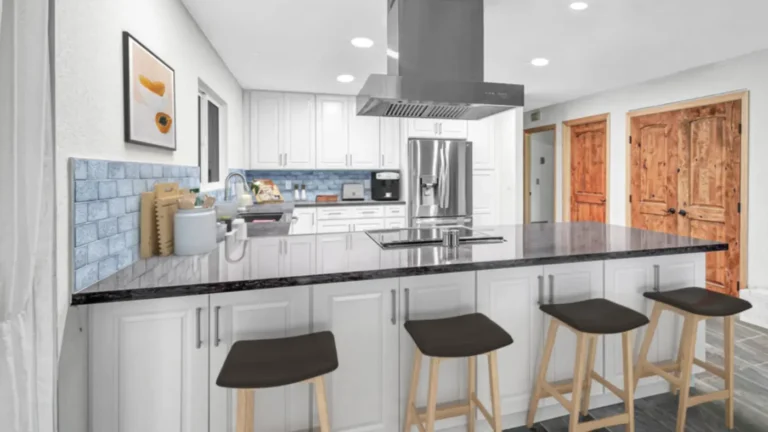 Dark countertop peninsula with four bar stools and a stainless steel island hood in a remodeled Laguna Hills kitchen