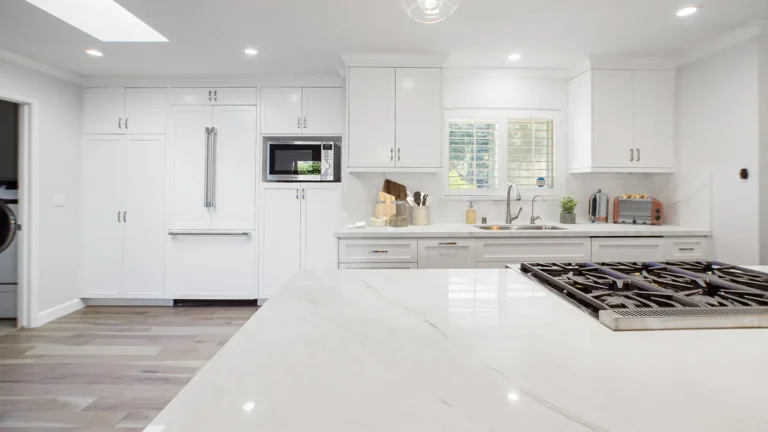 White veined island countertop facing white shaker cabinets and a panel-ready refrigerator in a Laguna Niguel kitchen
