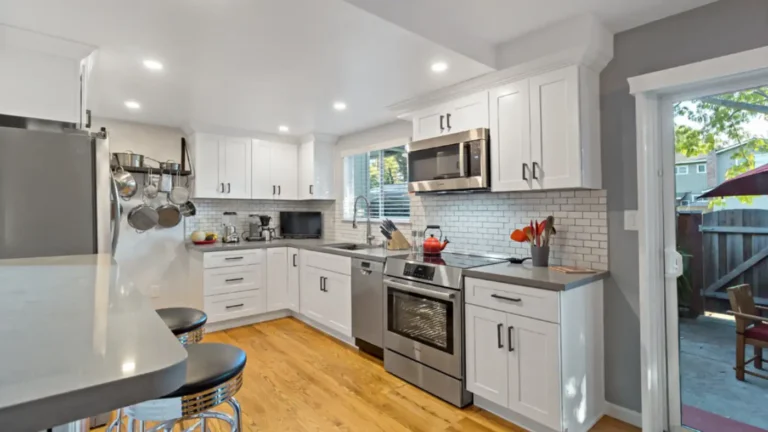 L-shaped run of white shaker cabinets beside a patio slider in a Laguna Niguel kitchen remodel with gray quartz counters