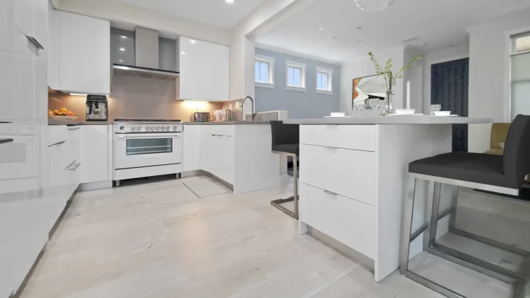 Light oak plank flooring runs past a white range and gloss cabinets in this open Mission Viejo kitchen remodel