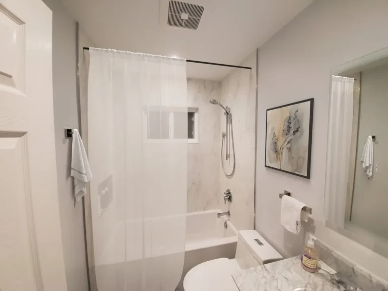Large-format porcelain tile tub shower with a window and handheld sprayer in a Lake Forest bathroom remodel.