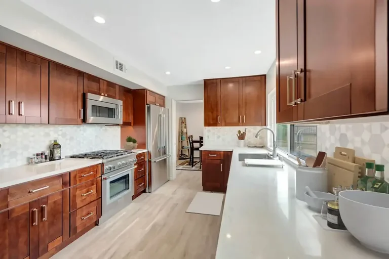 White quartz countertops and hexagon marble backsplash along walnut cabinets in a Mission Viejo galley kitchen remodel