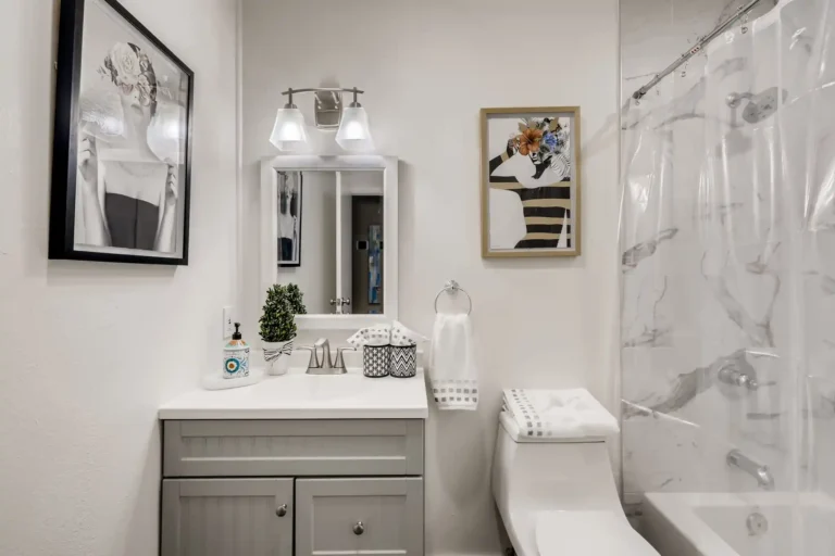 White vanity countertop and framed wall art beside the tiled tub surround in a San Clemente guest bathroom