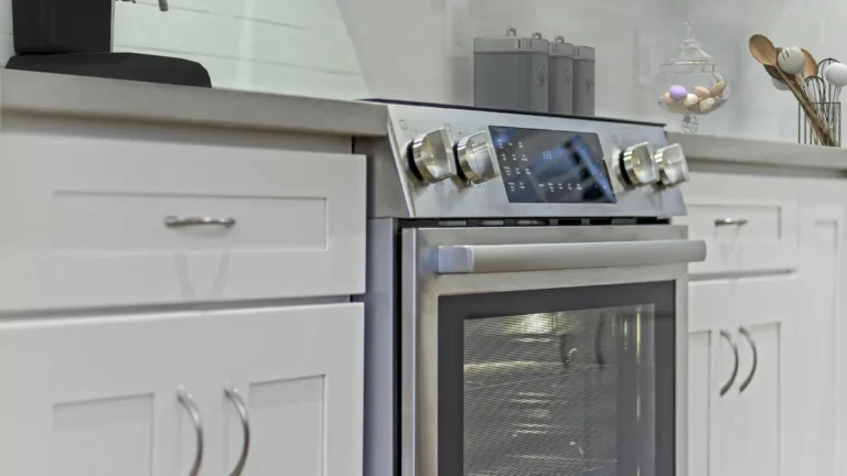 Close-up of a stainless steel electric range set between white shaker drawers in a Laguna Hills kitchen remodel