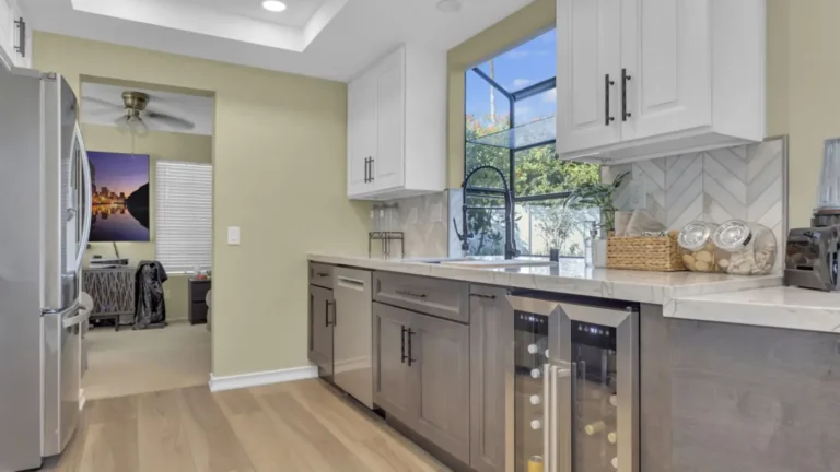Wine fridge and gray lower cabinets beneath quartzite countertops and a chevron backsplash in an Oceanside kitchen