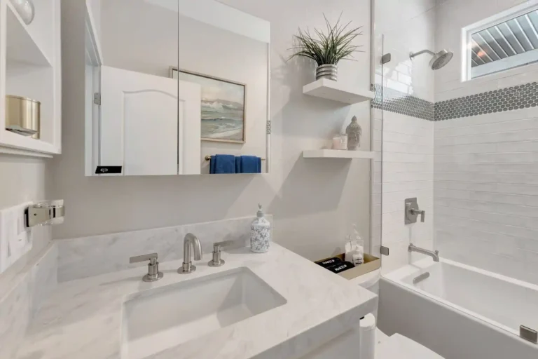Marble countertop and backsplash below a mirrored medicine cabinet in a Newport Beach guest bathroom remodel