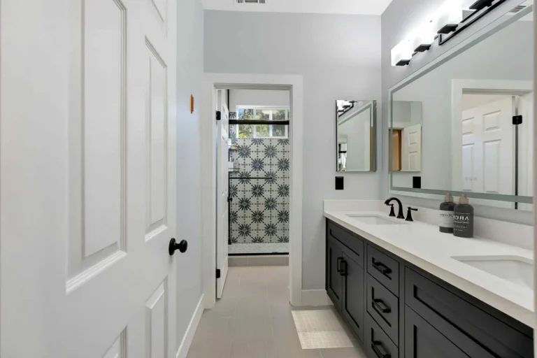 Long quartz-topped vanity leading through to a blue starburst tile shower in this remodeled San Clemente bathroom.