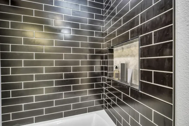 Recessed shower niche with hexagon mosaic backing set into glossy black subway tile in an Aliso Viejo bathroom