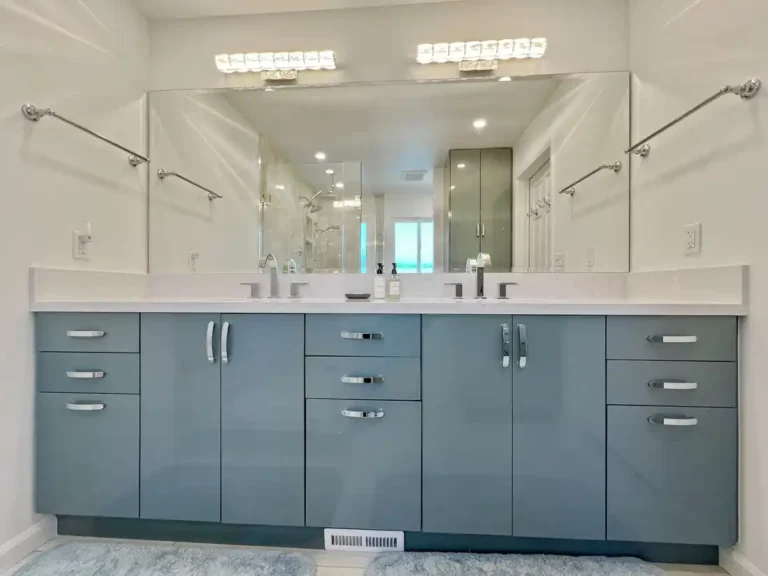 Blue flat panel double vanity with quartz countertop and a wide frameless mirror in a remodeled Aliso Viejo bathroom.