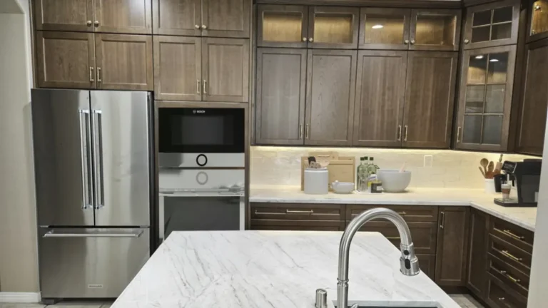 Stainless French door refrigerator and built-in wall ovens beside dark wood cabinets in a Costa Mesa kitchen remodel