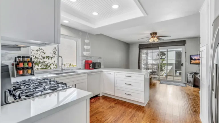 Recessed lighting in a white beadboard tray ceiling over a U-shaped Irvine kitchen that opens to the family room.