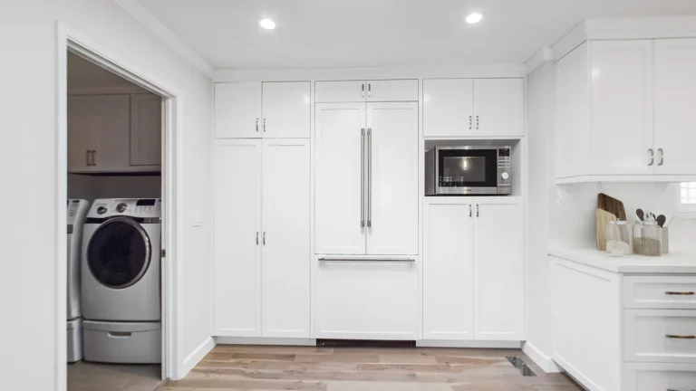 Panel-ready French door refrigerator between tall white pantry cabinets and a microwave niche in a Laguna Niguel kitchen