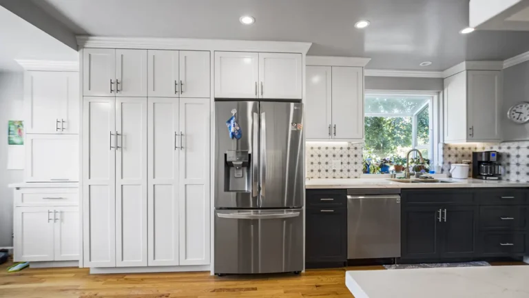 Floor-to-ceiling white pantry cabinets framing a stainless French door refrigerator in a Laguna Niguel kitchen remodel