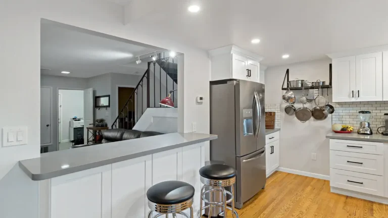 Gray quartz breakfast bar with chrome stools and a pass-through to the living room in a Laguna Niguel kitchen remodel