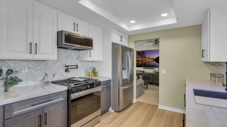 Marble chevron backsplash with a black pot filler over a gas range in a two-tone Oceanside kitchen remodel