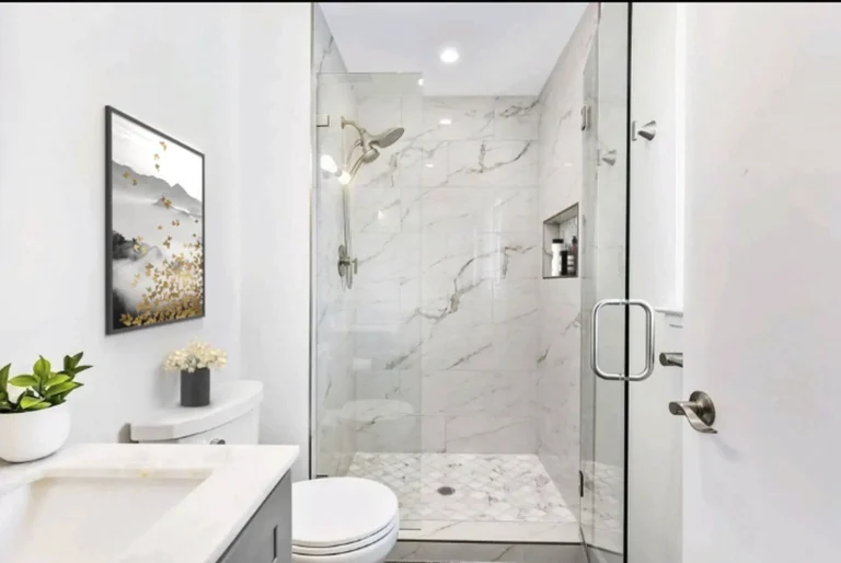 Glass-enclosed shower with large format marble wall tile and a recessed niche in a Laguna Niguel bathroom