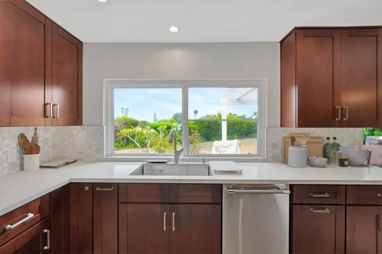 Stainless undermount sink beneath a garden view window with walnut cabinets in a remodeled Mission Viejo kitchen